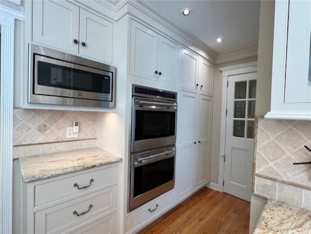 kitchen featuring stainless steel appliances, recessed lighting, backsplash, light wood-style floors, and light stone countertops