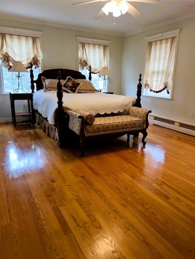 bedroom with a baseboard heating unit, ceiling fan, ornamental molding, and wood finished floors