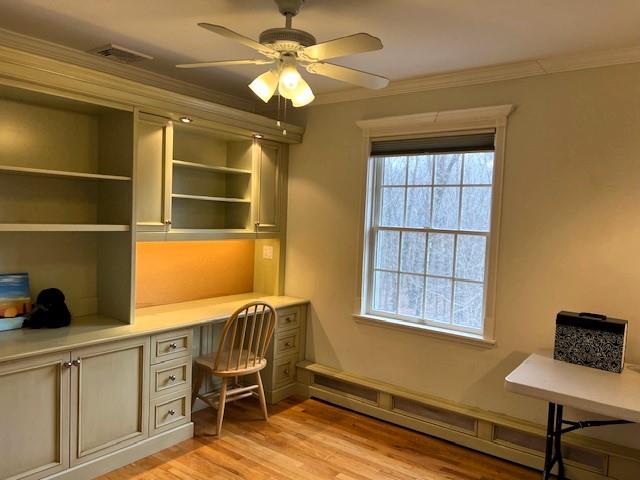 office area featuring visible vents, built in study area, ceiling fan, ornamental molding, and light wood-type flooring