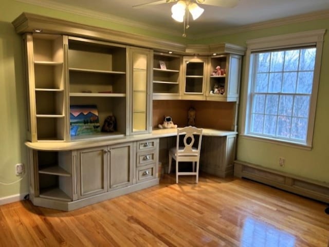 unfurnished office featuring ornamental molding, baseboard heating, built in study area, and a healthy amount of sunlight