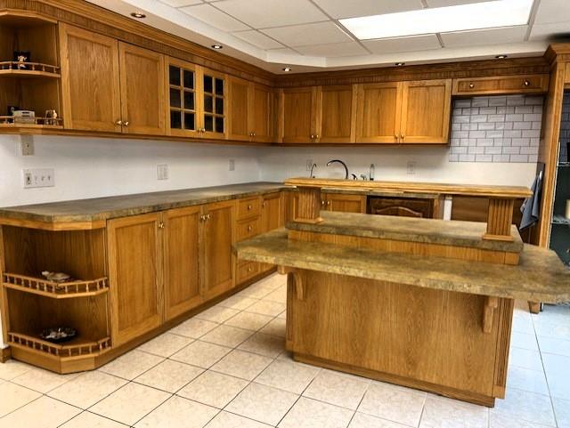 kitchen featuring brown cabinets, a kitchen bar, open shelves, and a sink