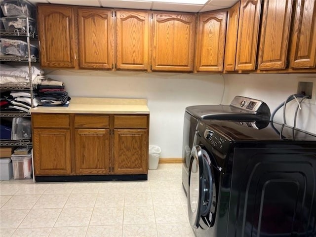 laundry area with light tile patterned floors, cabinet space, baseboards, and separate washer and dryer