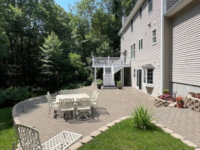 view of patio / terrace with outdoor dining space, stairway, and a wooden deck