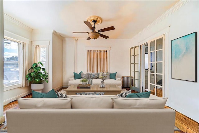 living area with ornamental molding, a ceiling fan, baseboards, and wood finished floors