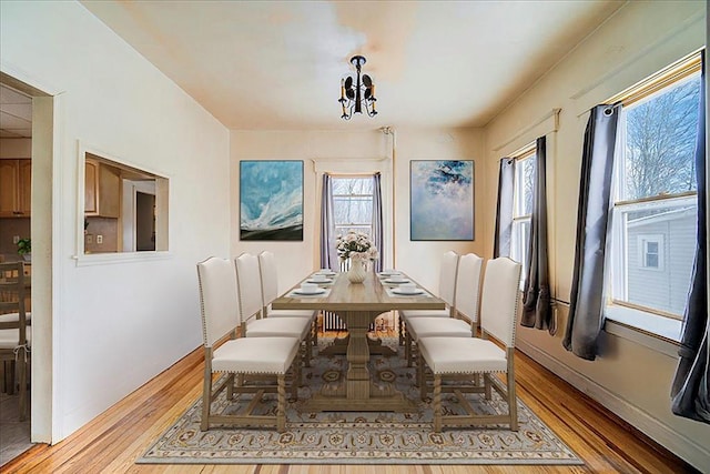 dining space featuring a chandelier, light wood finished floors, and baseboards