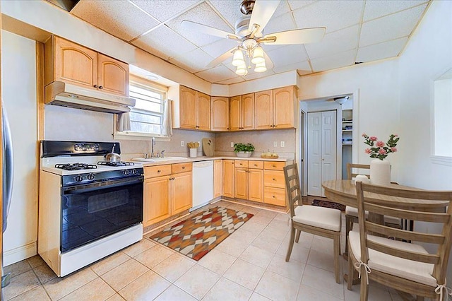 kitchen with light countertops, a sink, gas range, dishwasher, and under cabinet range hood