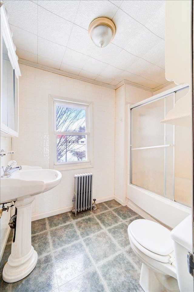 bathroom with toilet, radiator heating unit, and a shower with shower door