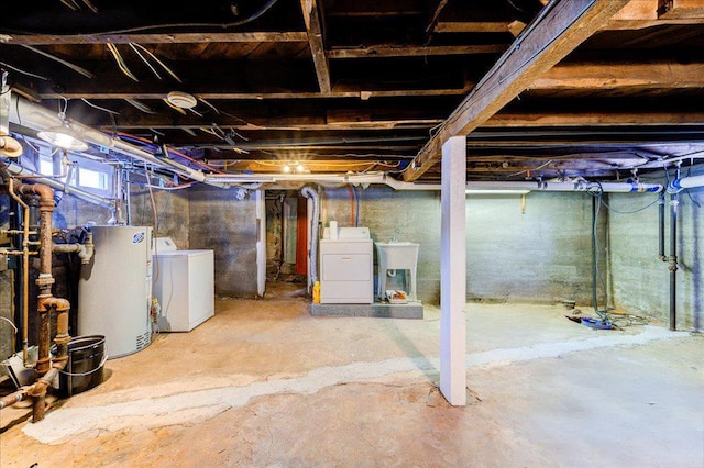 basement with washing machine and dryer, water heater, and a sink