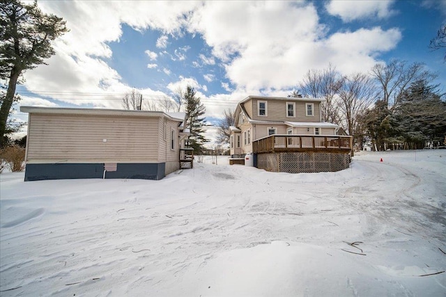 snow covered rear of property with a wooden deck