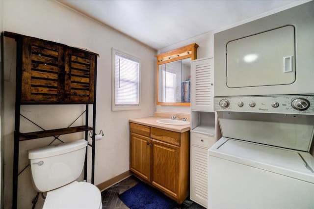 bathroom featuring toilet, baseboards, stacked washer / drying machine, and vanity