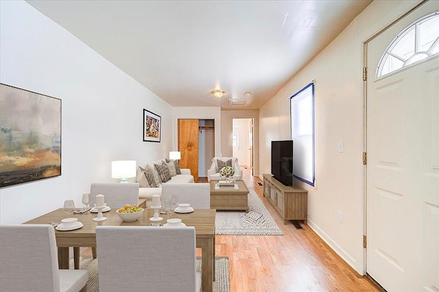 living area featuring light wood finished floors, baseboards, and a wealth of natural light