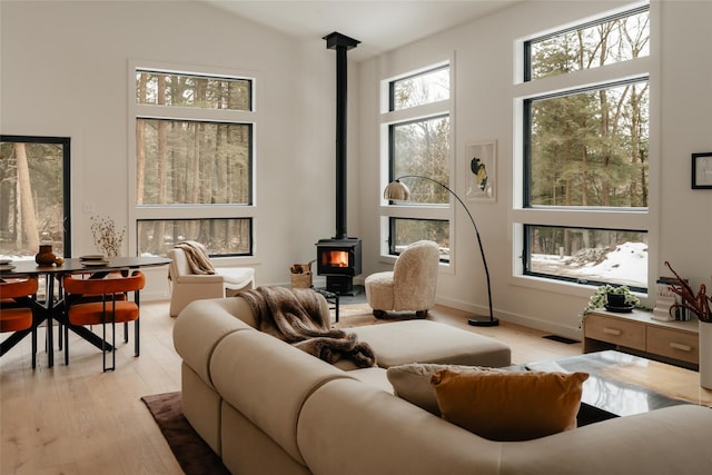 living room with a high ceiling, a wood stove, and light wood-style floors