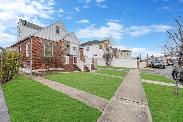 view of front facade featuring brick siding, a front yard, and fence