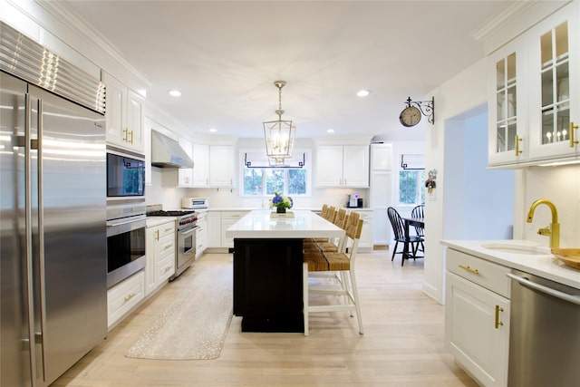 kitchen with light countertops, white cabinetry, a sink, built in appliances, and extractor fan