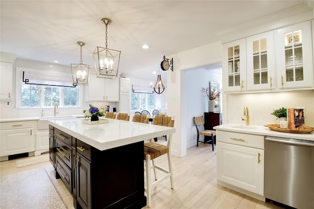 kitchen featuring a sink, white cabinetry, a breakfast bar area, and dishwasher