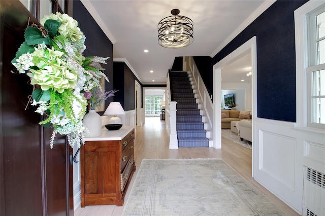 foyer with radiator, crown molding, and a decorative wall