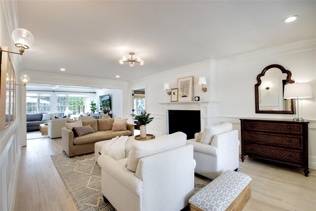 living area featuring a chandelier, recessed lighting, ornamental molding, and light wood-style flooring