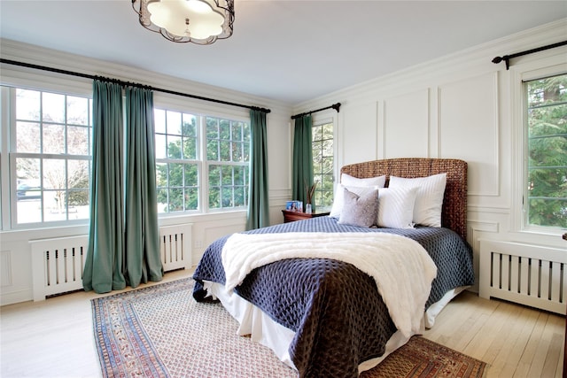 bedroom with radiator, multiple windows, and a decorative wall