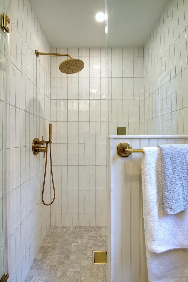 full bathroom featuring tiled shower and tile walls