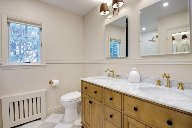 full bathroom with wainscoting, a sink, toilet, and double vanity