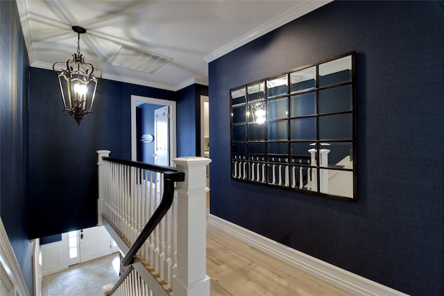 hall with baseboards, wood finished floors, crown molding, an upstairs landing, and a notable chandelier