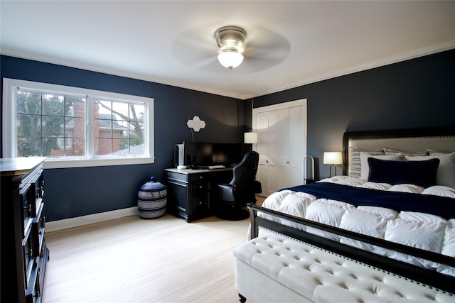 bedroom with light wood-style flooring, crown molding, baseboards, and a closet