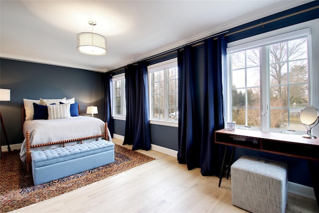 bedroom with multiple windows, crown molding, light wood-style flooring, and baseboards