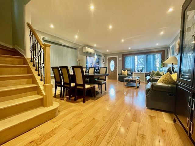 living room with stairs, crown molding, an AC wall unit, light wood-style floors, and recessed lighting