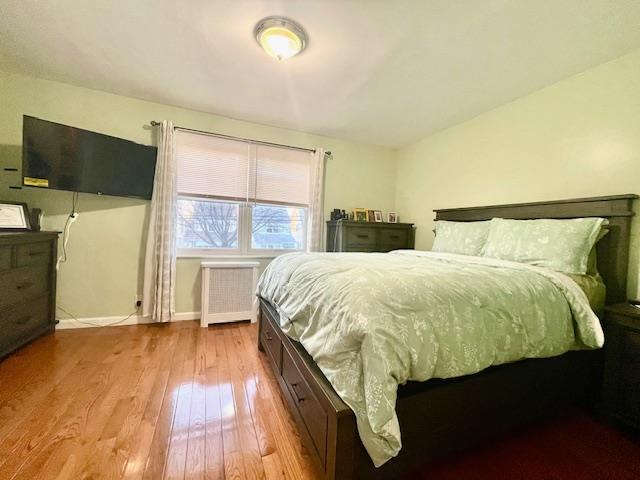 bedroom featuring baseboards, hardwood / wood-style floors, and radiator