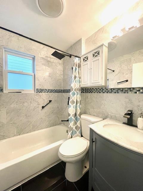 full bath with tile walls, shower / bathtub combination with curtain, backsplash, toilet, and vanity