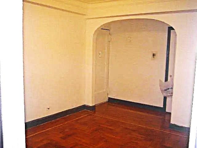 unfurnished room featuring arched walkways and dark wood-style flooring