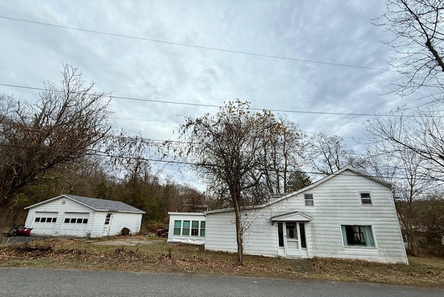 view of front of house with a detached garage and an outbuilding