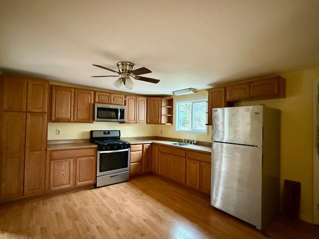 kitchen with brown cabinets, open shelves, appliances with stainless steel finishes, light wood-style floors, and a sink