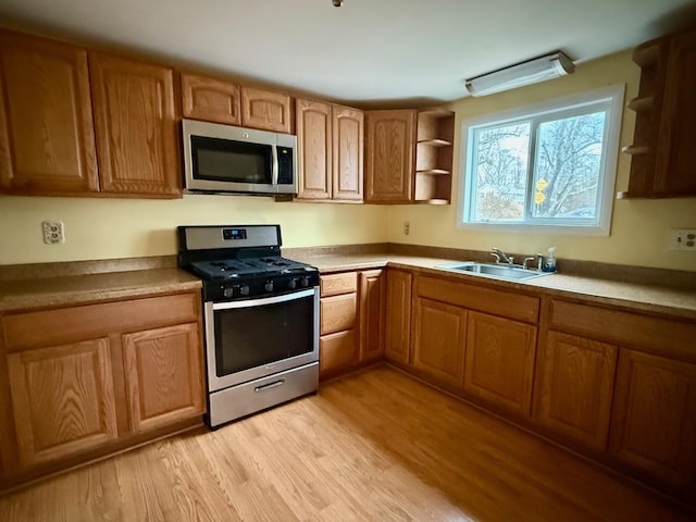 kitchen with brown cabinets, stainless steel appliances, light wood-type flooring, open shelves, and a sink