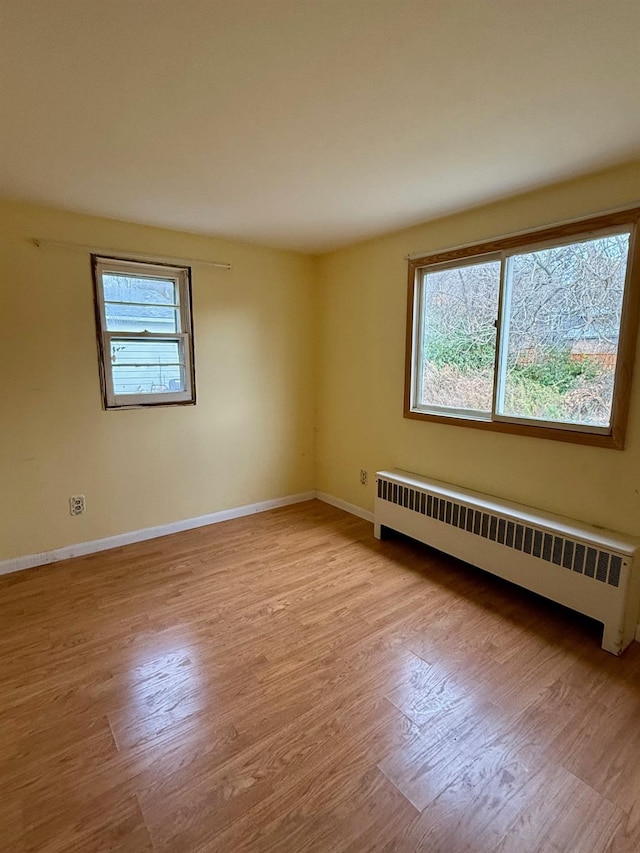 empty room with radiator, baseboards, and wood finished floors