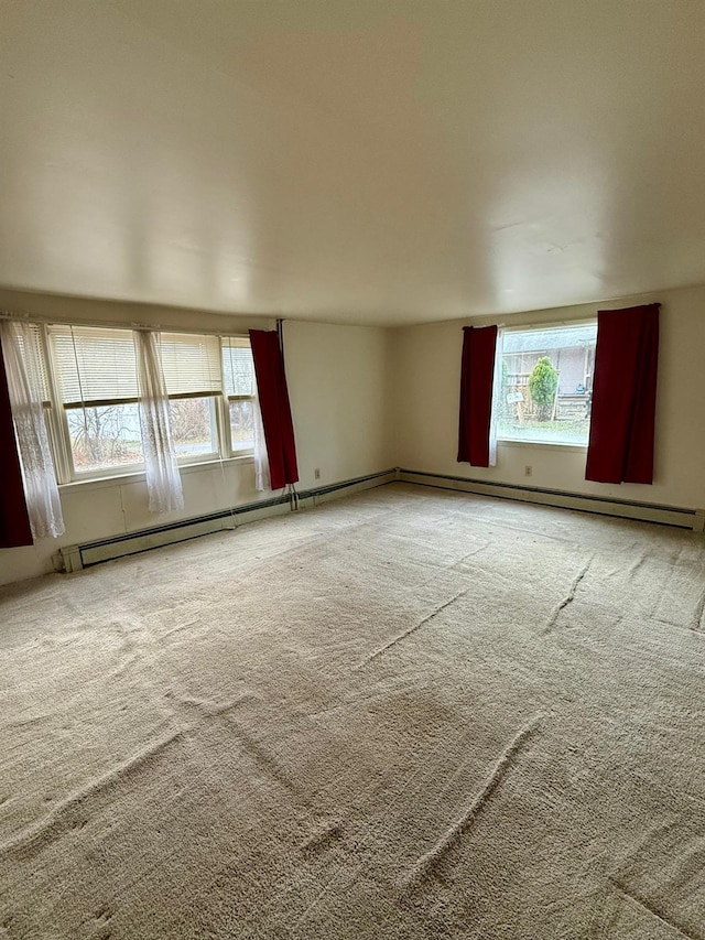 carpeted empty room with a baseboard heating unit and a healthy amount of sunlight