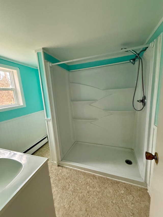 full bathroom featuring a wainscoted wall, walk in shower, baseboard heating, and vanity