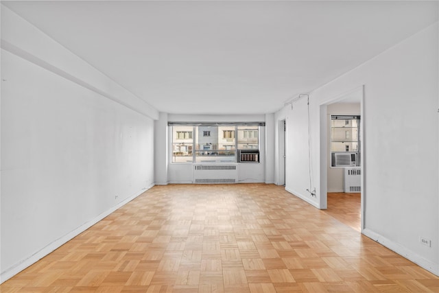 unfurnished living room with cooling unit, radiator heating unit, and baseboards