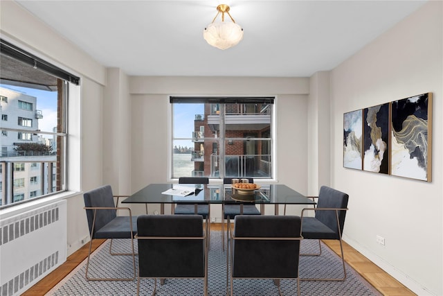 dining space featuring baseboards, radiator, and a healthy amount of sunlight