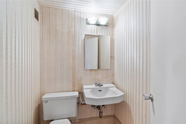 half bath featuring a sink, visible vents, and toilet