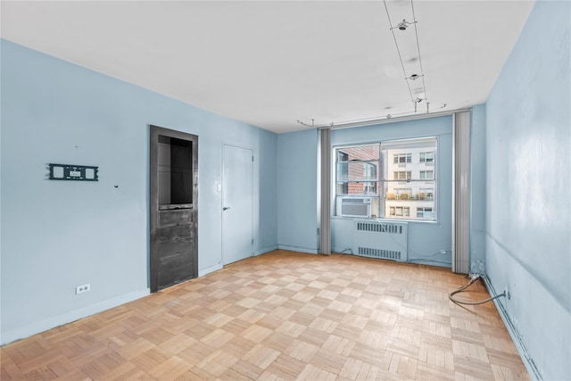 spare room featuring cooling unit, baseboards, and radiator heating unit