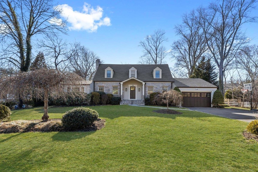 view of front of house featuring aphalt driveway, an attached garage, a front yard, and a chimney