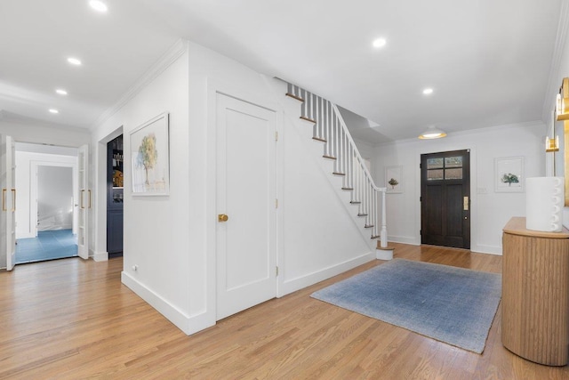 foyer entrance with recessed lighting, stairway, crown molding, light wood finished floors, and baseboards