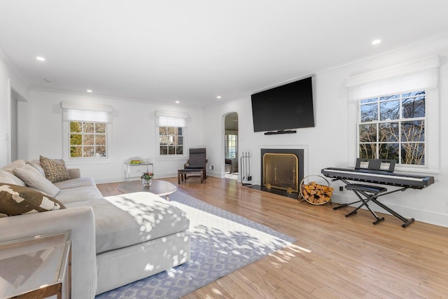 living area with a fireplace with flush hearth, recessed lighting, crown molding, and wood finished floors