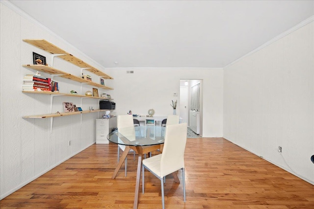 dining space with light wood-type flooring, visible vents, and ornamental molding