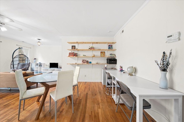 dining space with ceiling fan, crown molding, and wood finished floors