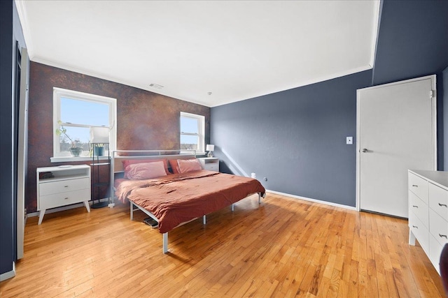 bedroom featuring baseboards, visible vents, light wood-style flooring, and crown molding