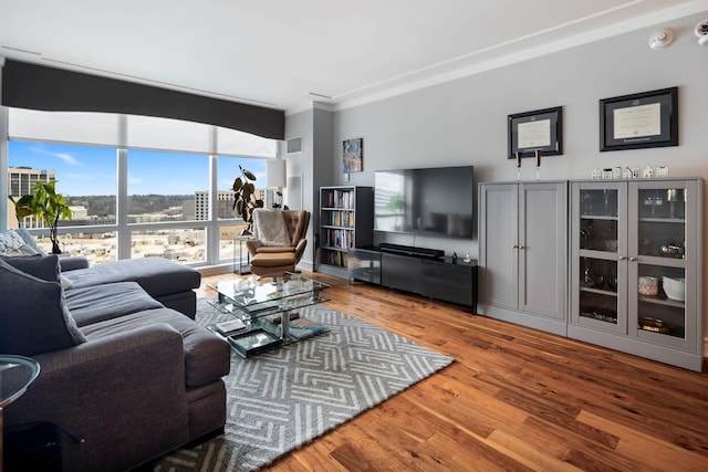 living area with ornamental molding, wood finished floors, visible vents, and floor to ceiling windows