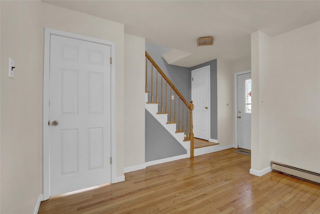 entryway with light wood finished floors, stairs, baseboards, and baseboard heating