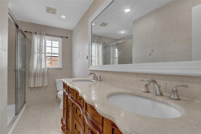 bathroom featuring toilet, a stall shower, a sink, and tile walls